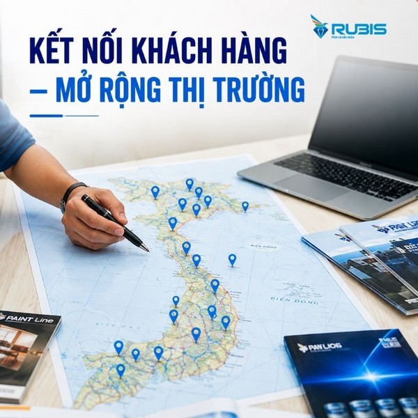 Bàn làm việc với bản đồ Việt Nam được đánh dấu nhiều vị trí, nhân viên kinh doanh đang dùng bút chỉ trên bản đồ, bên cạnh là laptop và tài liệu giới thiệu sản phẩm.